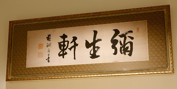 写真：筆文字で「彌生軒」と書かれている掛け軸が額に入れてある